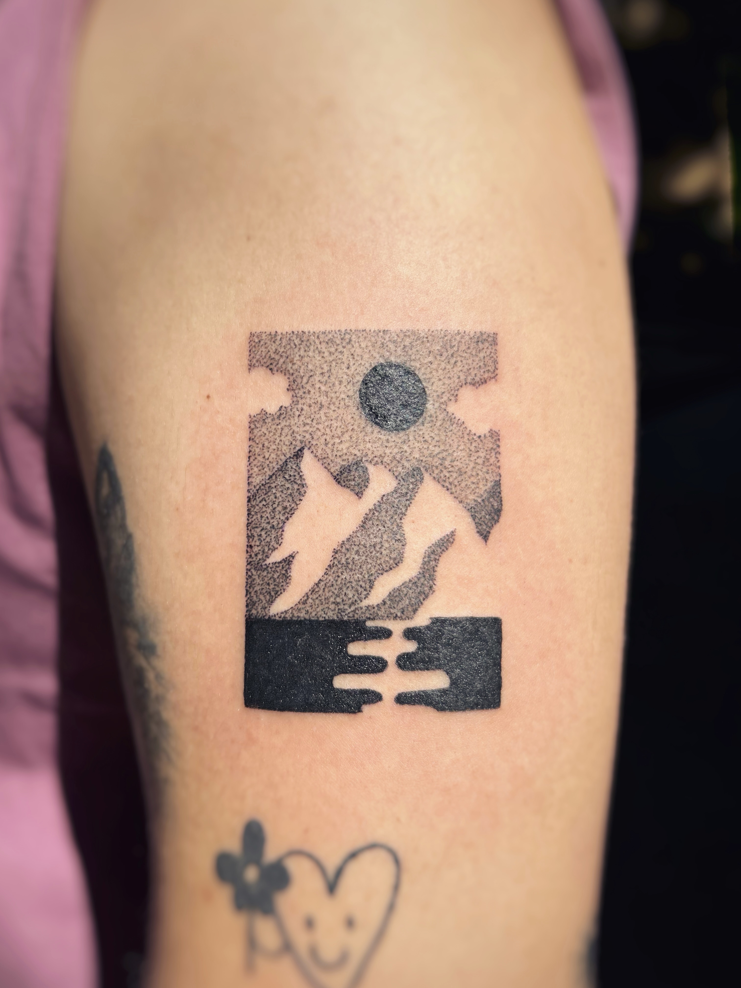 Tatouage paysage de montagne et lac dans un cadre, dotwork noir et gris sur le bras