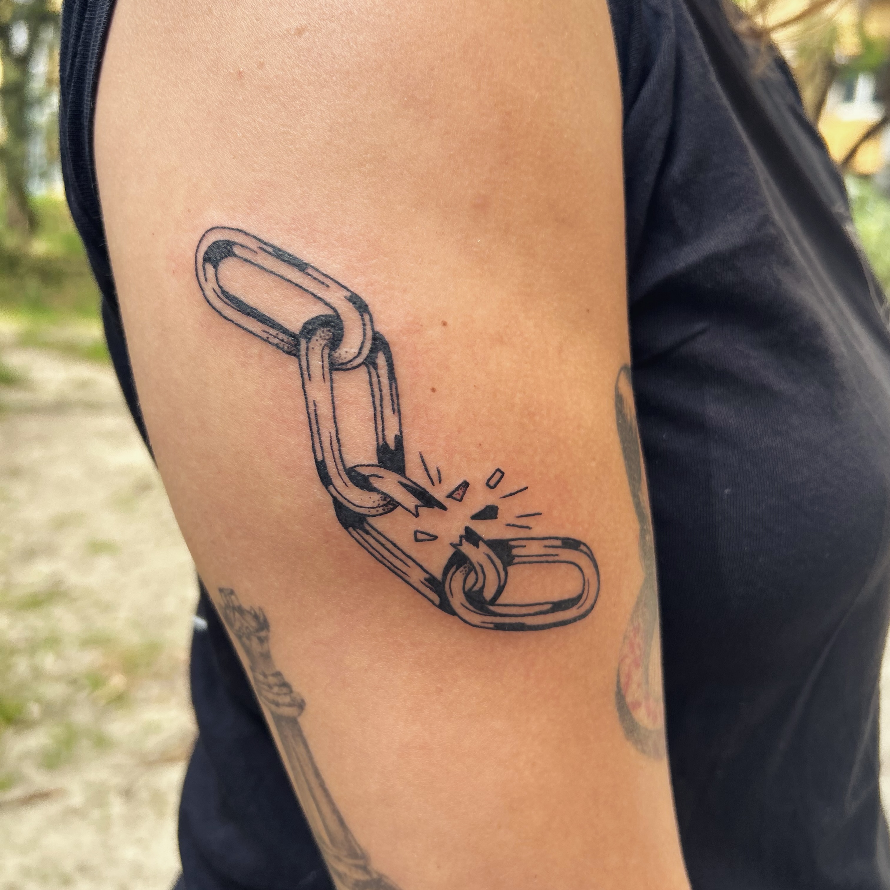 Tatouage chaine brisee sur le bras, blackwork noir et gris